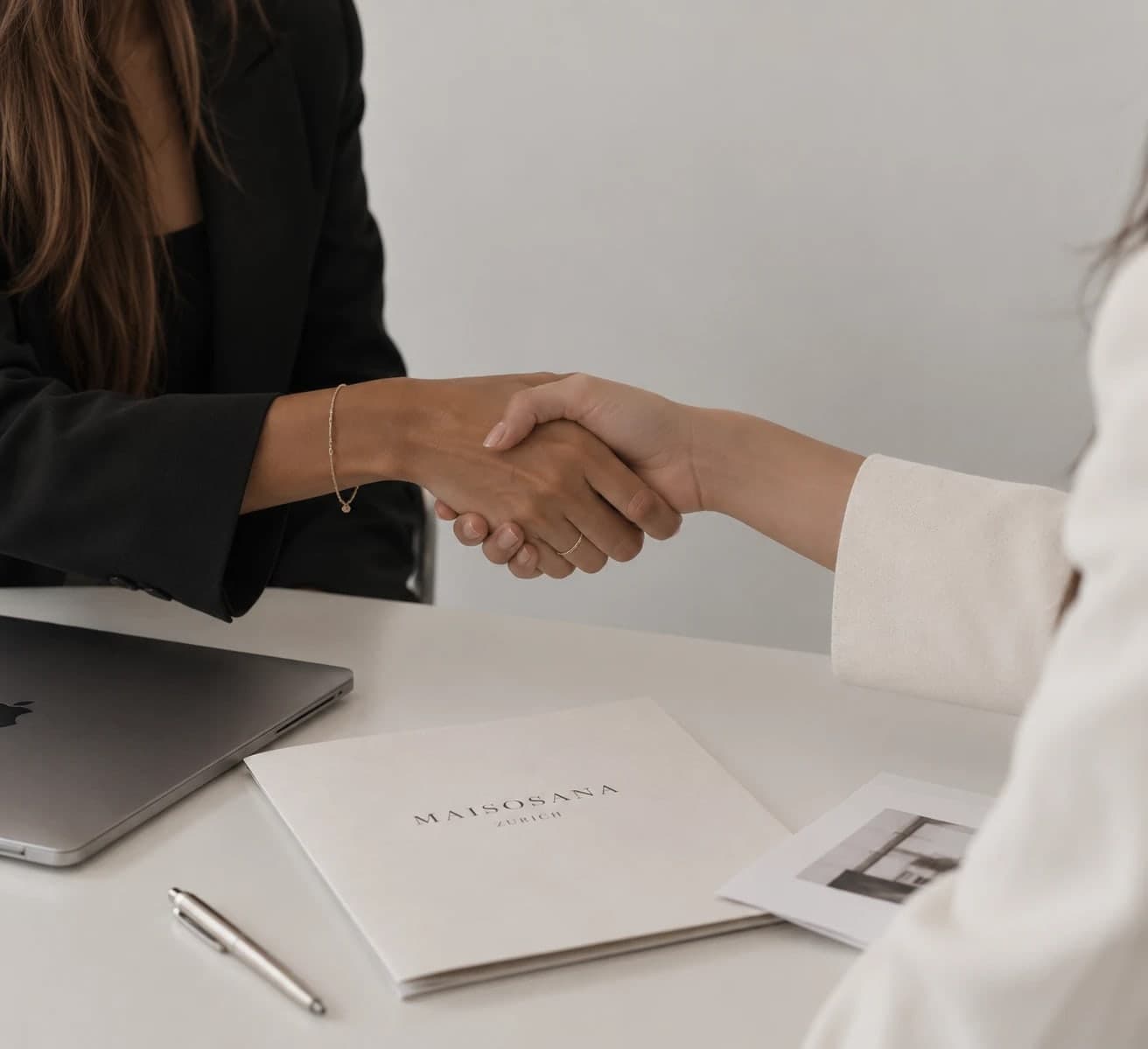 Handschlag zwischen Designerin und Kundin am Schreibtisch