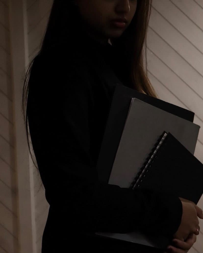 Eladsana Kuganesan im Halbschatten mit Notizbüchern und Mappen im Arm